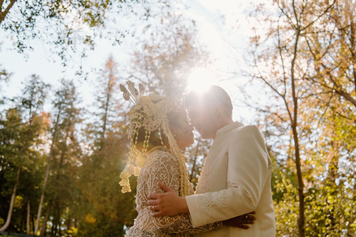 The bride and the groom kiss as the sun shines bright and luxuriant trees dance in the manicured Scarboro Golf & Country Club