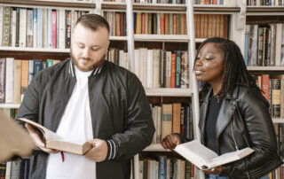a man and woman standing in front of a bookshelf